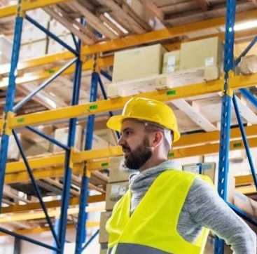 worker wearing high vis in front of shelves at a warehouse