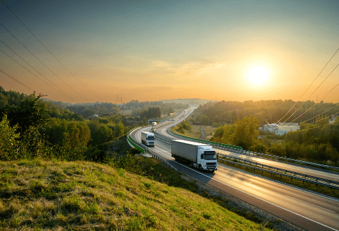 delivery trucks on a high way with the sun setting