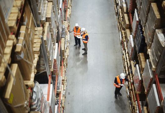 three workers standing in a aisle of a warehouse