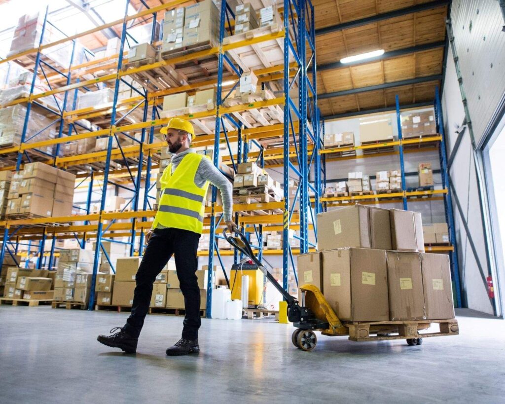 worker in high vis towing boxes in a warehouse